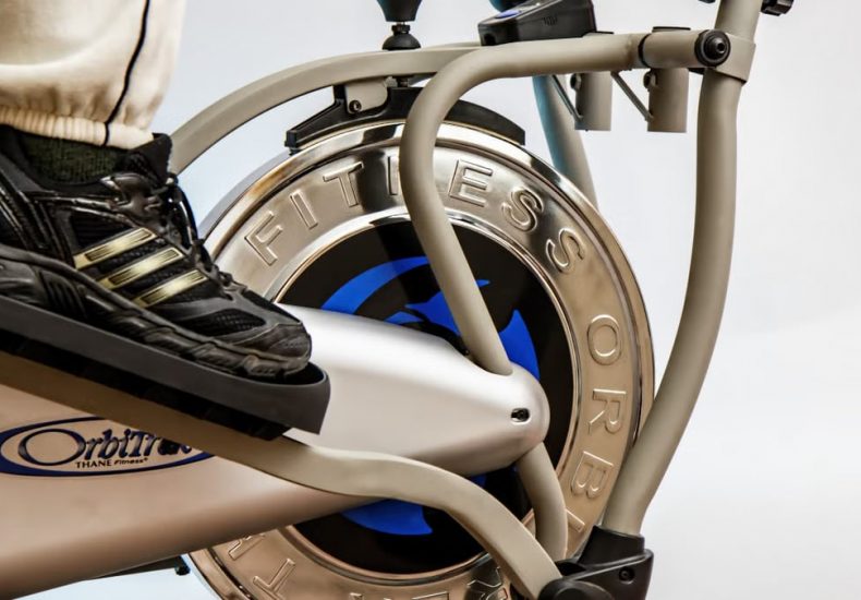 Foot on pedal of elliptical trainer showcasing fitness equipment and footwear close-up.